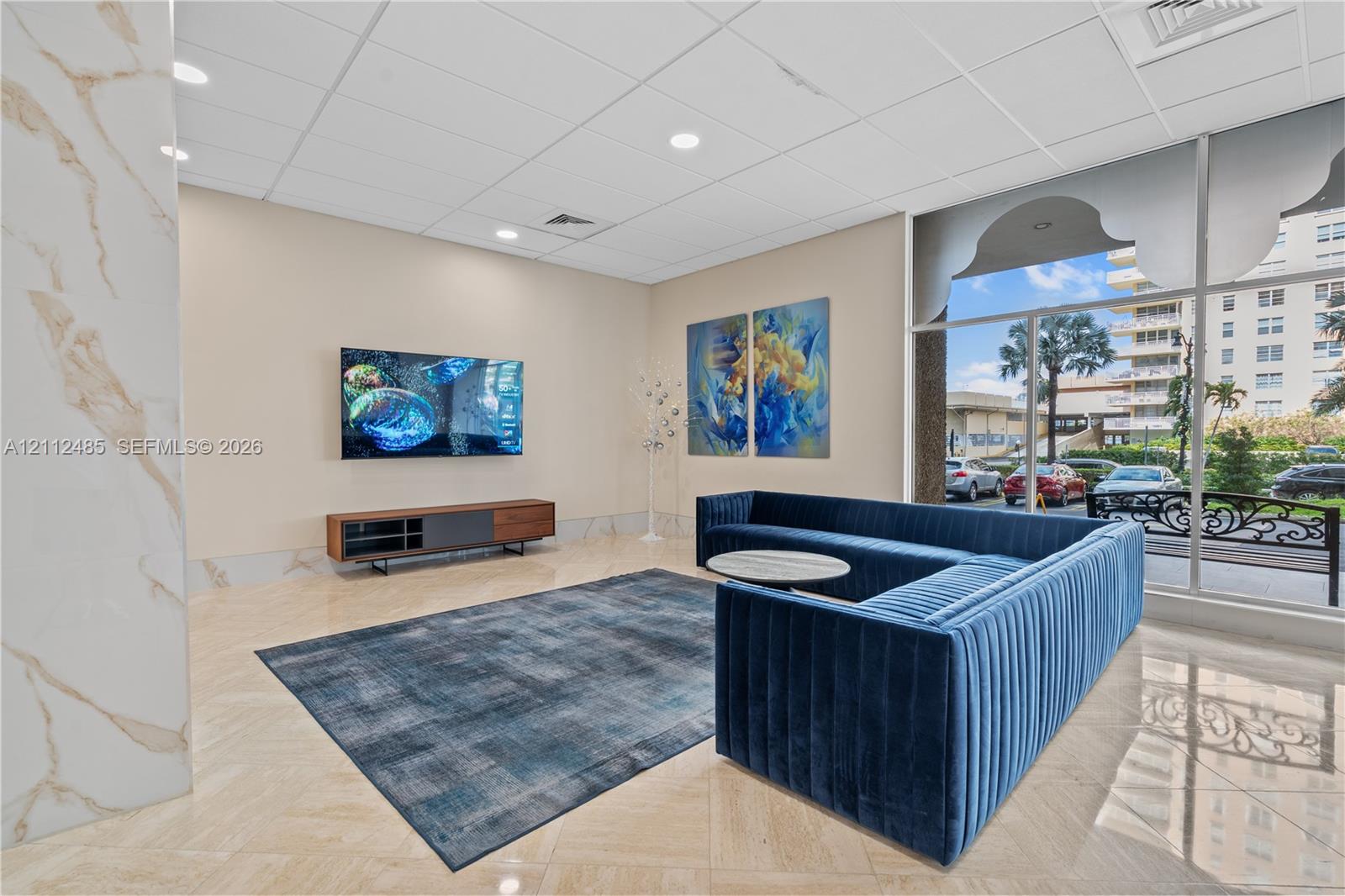 Common area featuring polished stone tile flooring, floor-to-ceiling glass windows, recessed ceiling lighting, and a column accented with decorative stone cladding
