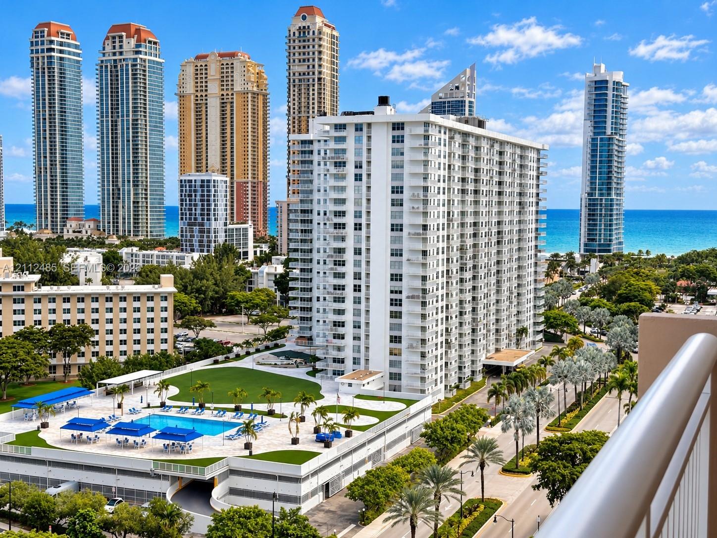 High-rise residential exterior featuring private balconies, an elevated pool deck, manicured turf lawns, and proximity to the oceanfront