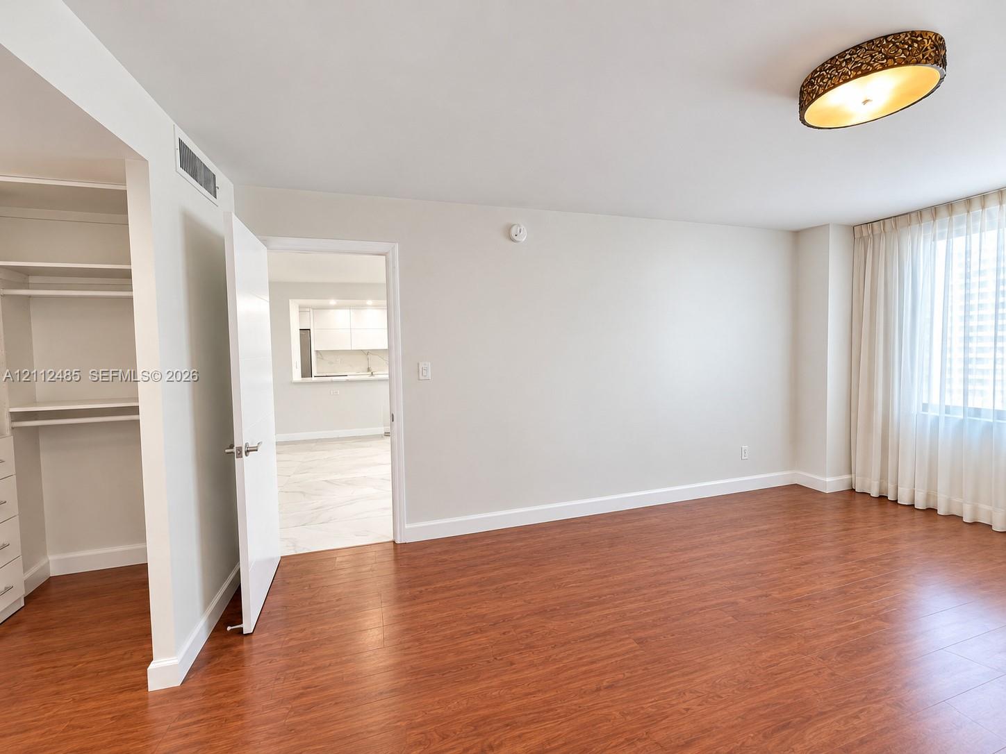 Wood-finish flooring, built-in shelving unit, and decorative semi-flush mount ceiling fixture