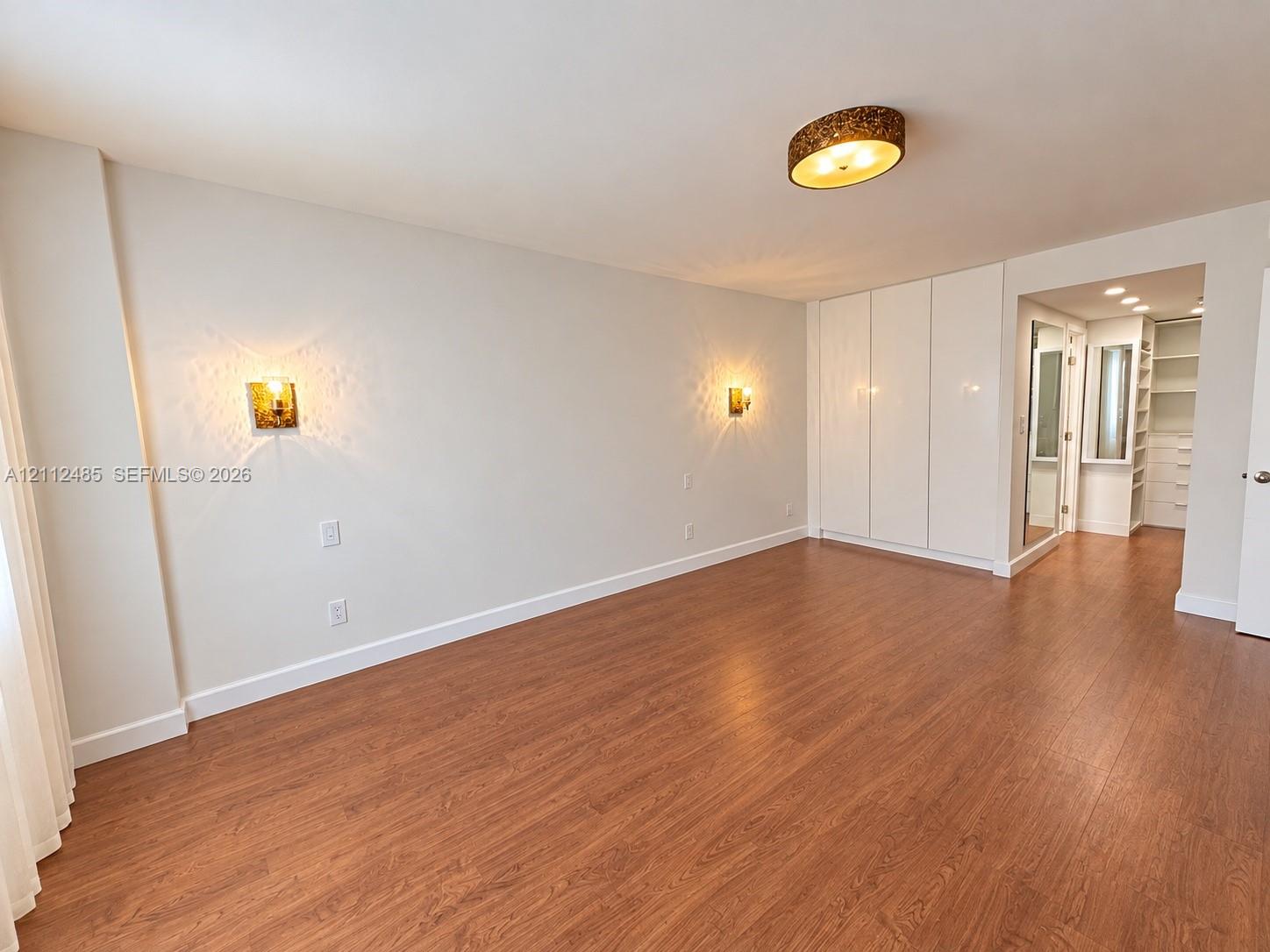 Wood-finish flooring, built-in floor-to-ceiling cabinetry, recessed lighting, and wall-mounted sconces