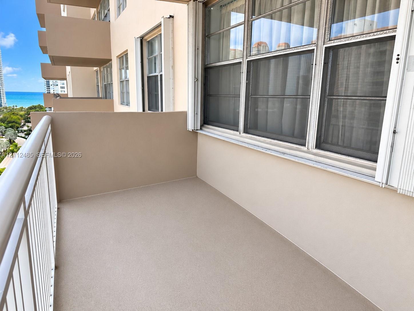 Private balcony featuring a solid surface floor, metal railing, and aluminum-frame windows