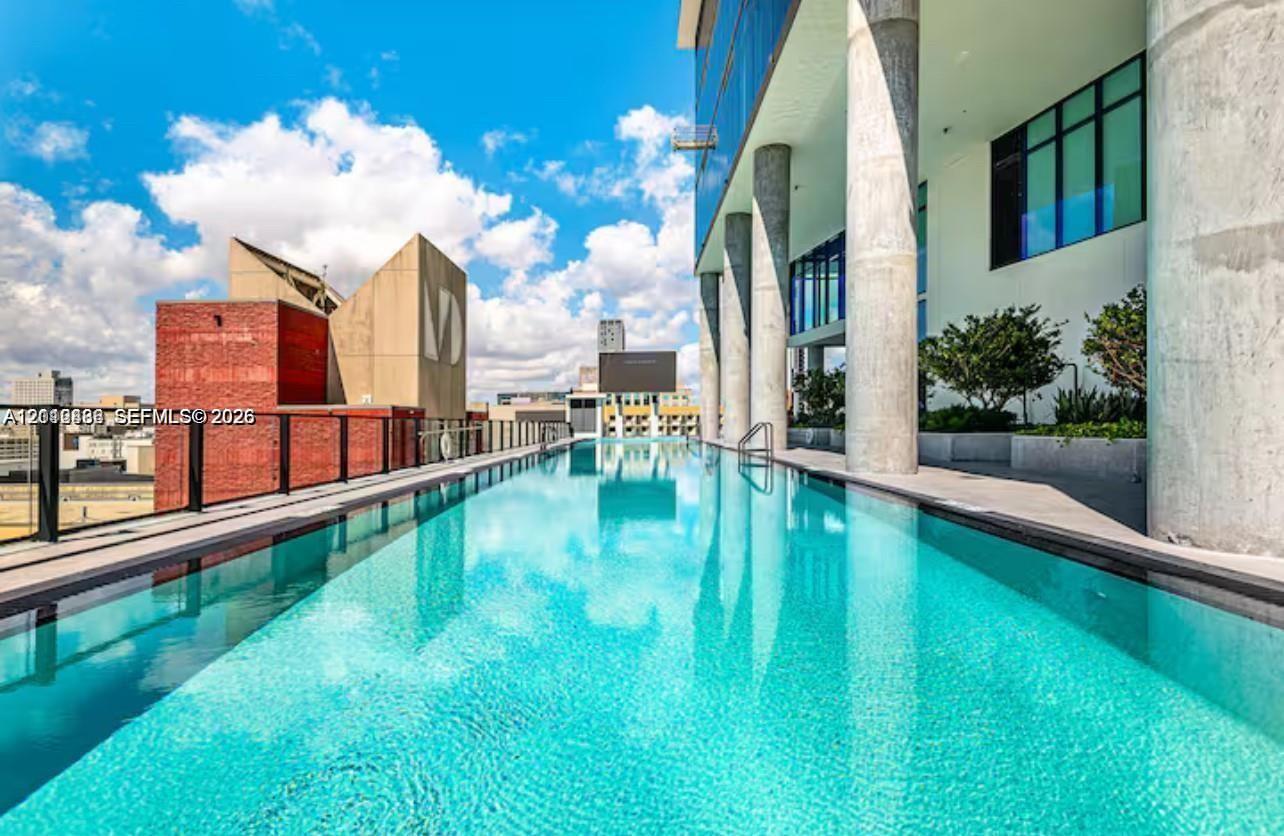 Infinity-edge lap pool featuring integrated structural columns, metal perimeter railing, and built-in landscape planters