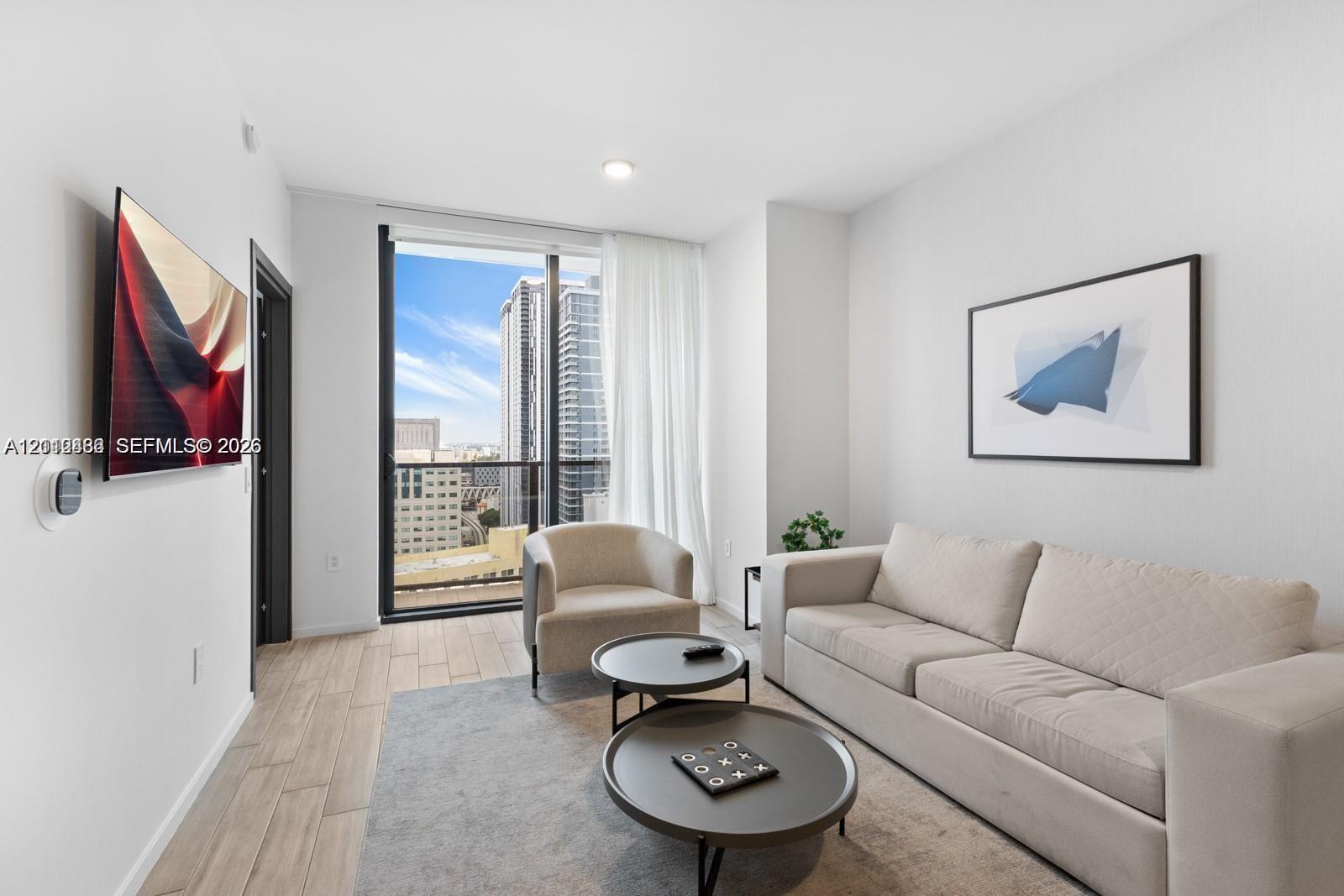 Floor-to-ceiling glass panel door, wood-finish flooring, recessed lighting, and a private balcony featuring urban scenery