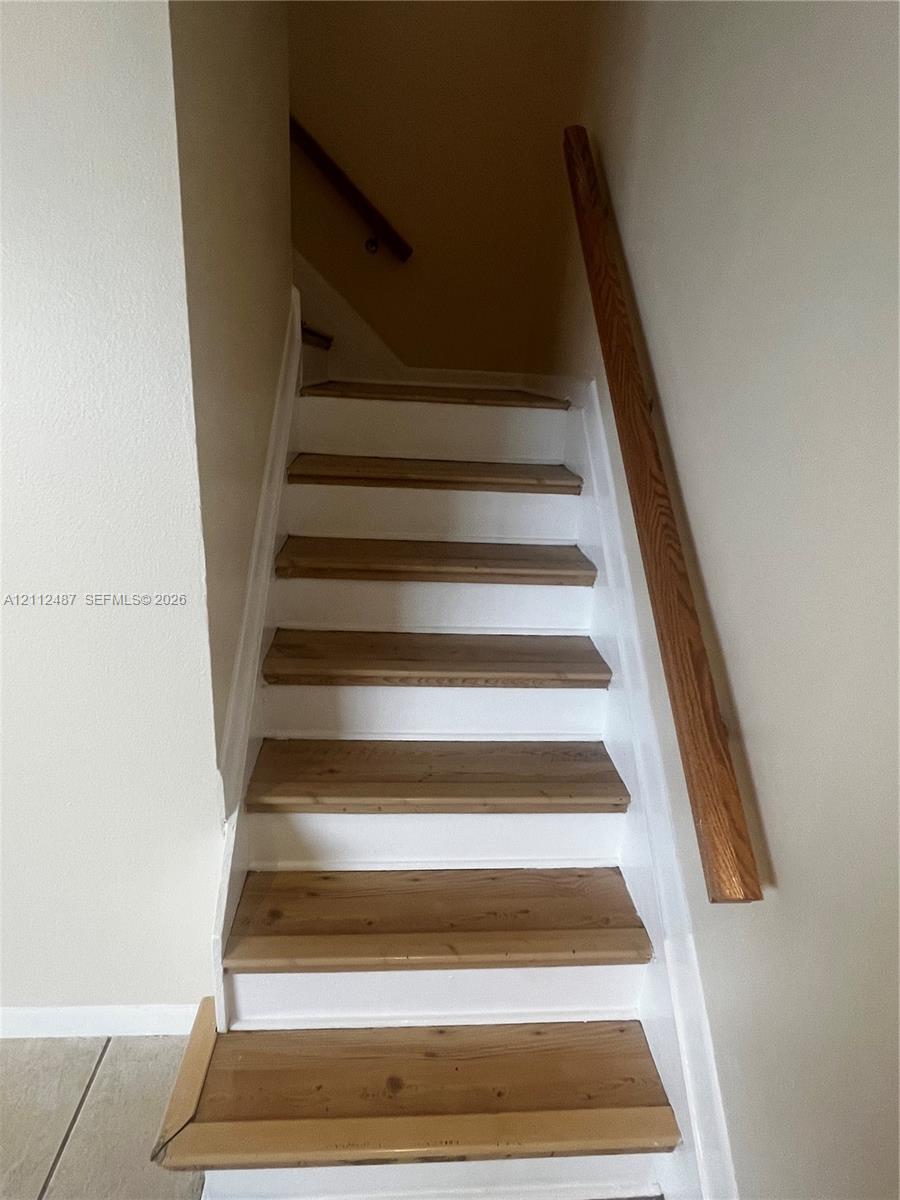 Staircase featuring wood-finish treads, white risers, and a mounted wooden handrail