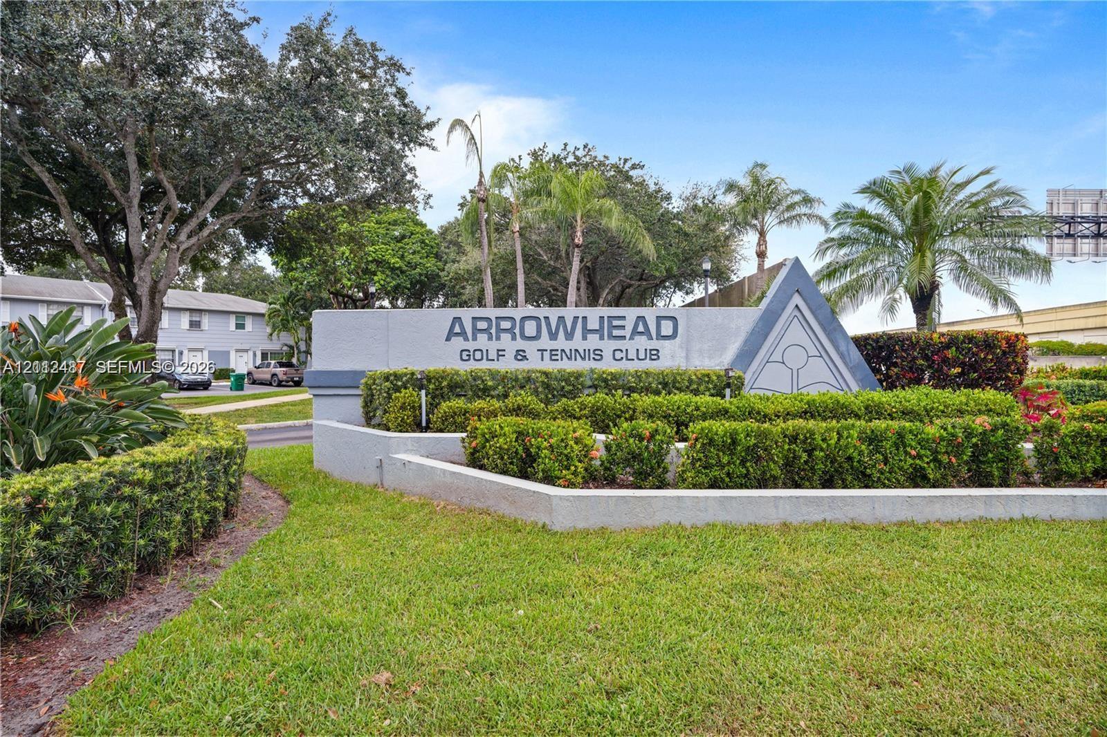 Monolithic concrete entrance monument featuring professional landscaping with manicured hedges and mature palm trees Monolithic concrete entrance monument featuring professional landscaping with manicured hedges and mature palm trees