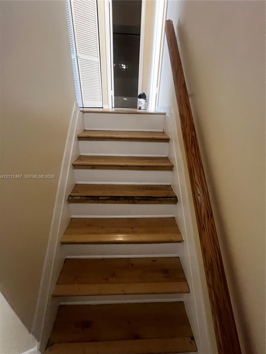 Staircase featuring natural wood treads, white risers, and a mounted wood handrail