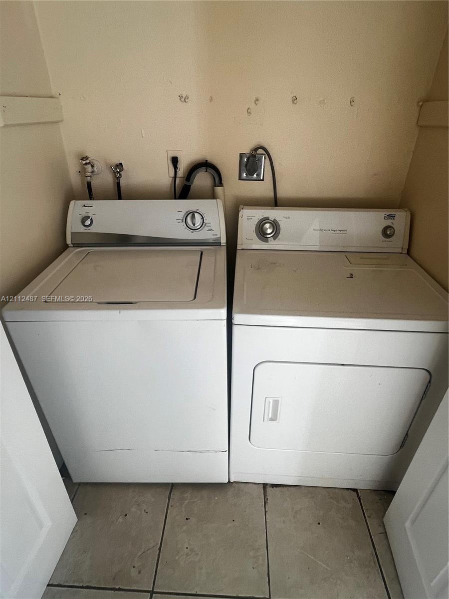 Laundry area featuring side-by-side washer and dryer units with a tiled floor Laundry area featuring side-by-side washer and dryer units with a tiled floor