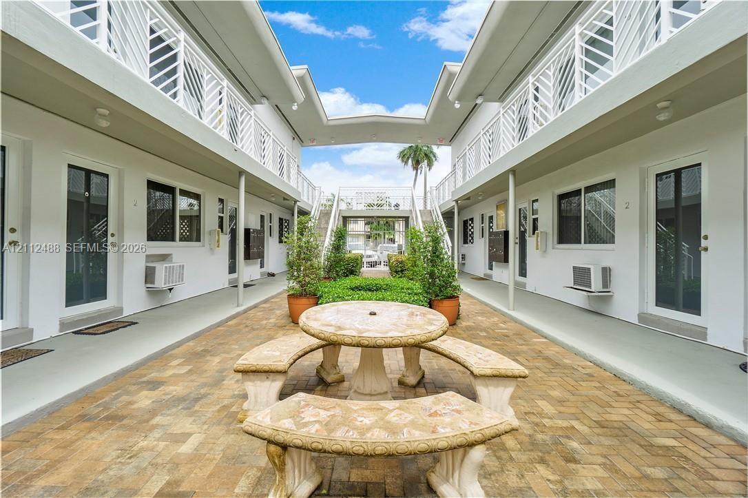 Courtyard area featuring brick paver flooring, stone masonry seating, metal lattice railings, and exterior walkways Courtyard area featuring brick paver flooring, stone masonry seating, metal lattice railings, and exterior walkways