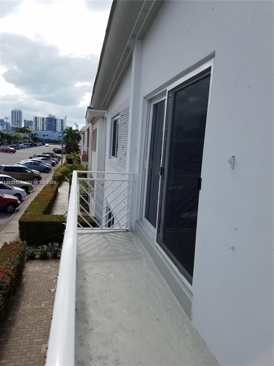 Exterior balcony featuring white metal railings and a sliding glass door