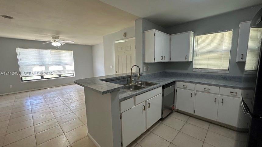 Kitchen featuring white cabinetry, solid-surface countertops, dual-basin stainless steel sink, and tile flooring