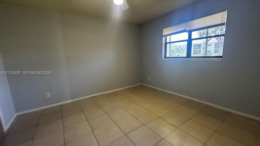 Neutral-toned interior featuring ceramic tile flooring, a dual-pane window with integrated horizontal blinds, and a ceiling fan with light fixture