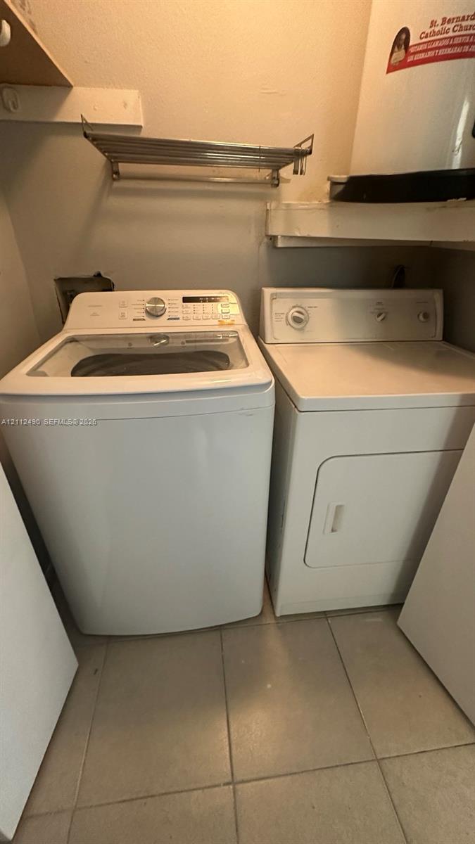 Utility area featuring white tile flooring, built-in wall shelving, and a wall-mounted metal rack