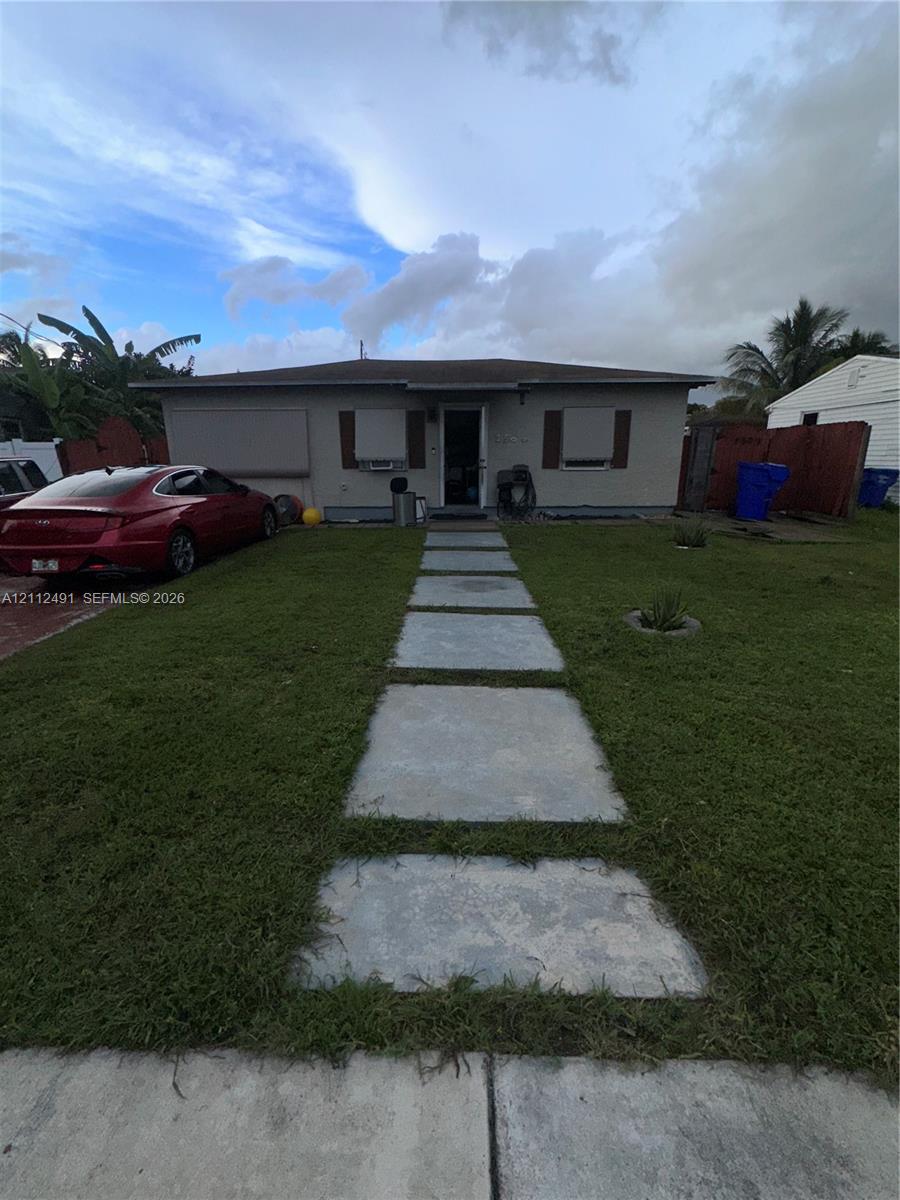 Single-story residence featuring a concrete paver walkway, wood-finish exterior window shutters, and a concrete driveway
