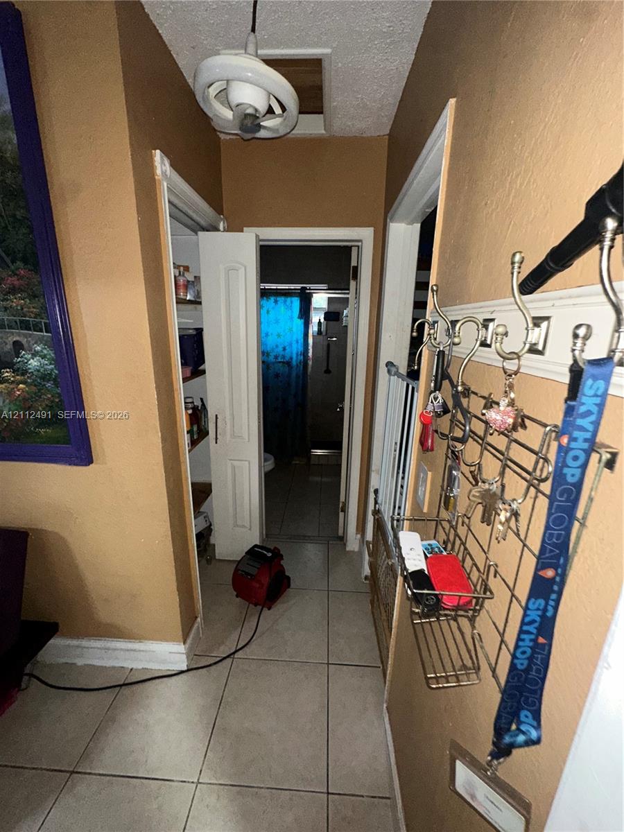 Ceramic tile flooring, built-in storage closet with shelving, and overhead lighting