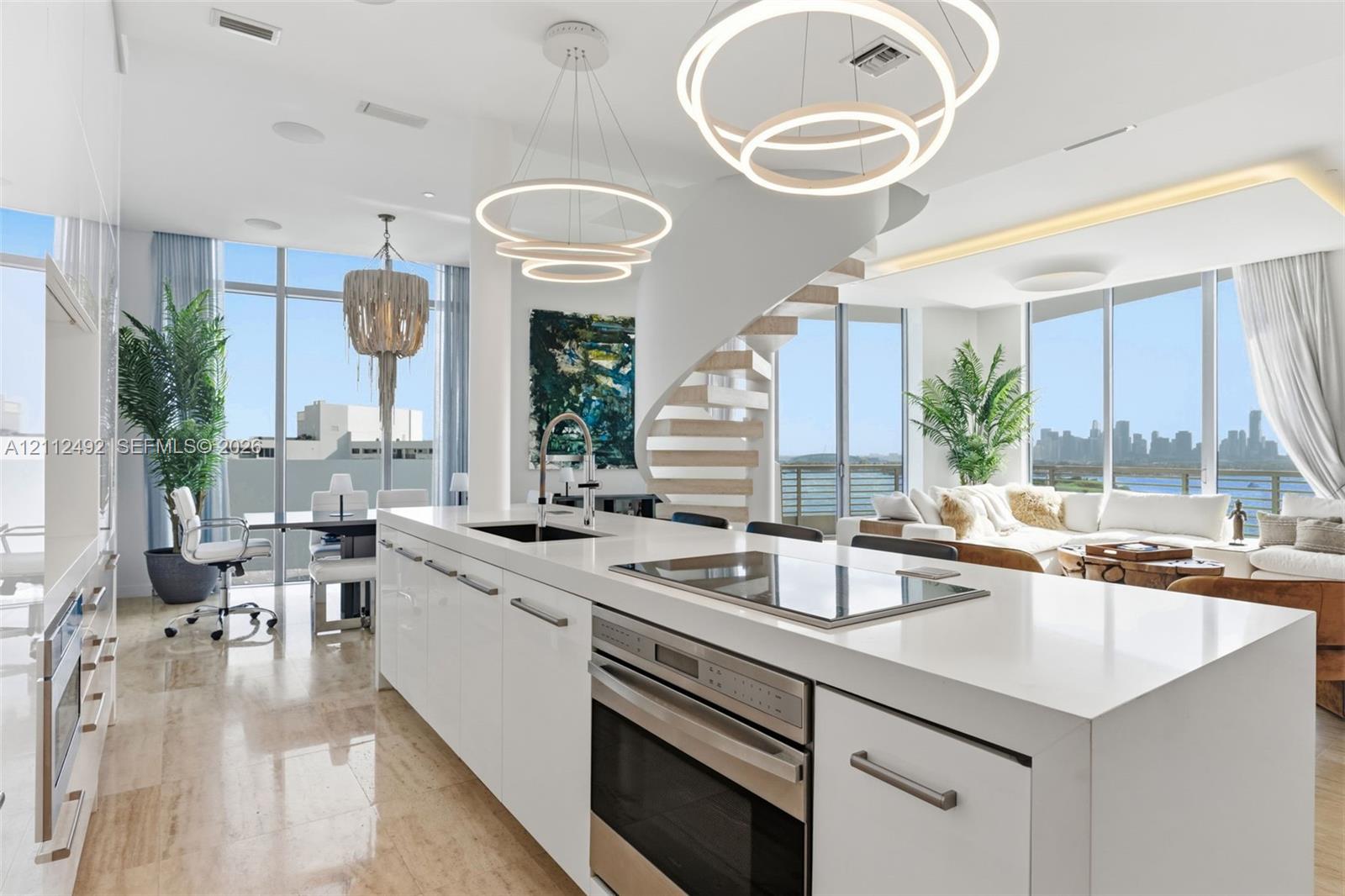 Kitchen featuring a center island with a stone countertop, built-in cooktop, and under-counter oven, floor-to-ceiling windows, polished stone flooring, and a floating spiral staircase