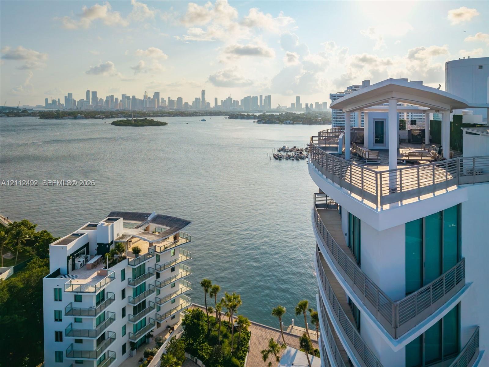 High-rise architecture featuring expansive rooftop terraces, glass-railing balconies, floor-to-ceiling windows, and waterfront positioning overlooking the city skyline