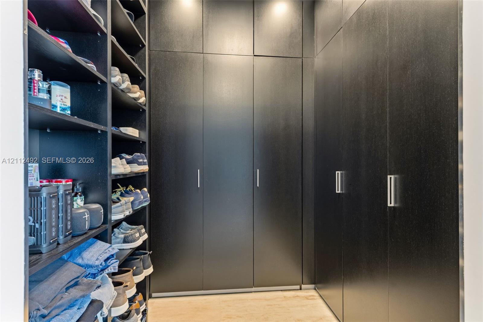 Custom black cabinetry featuring floor-to-ceiling storage, sleek metallic hardware, and integrated open shelving