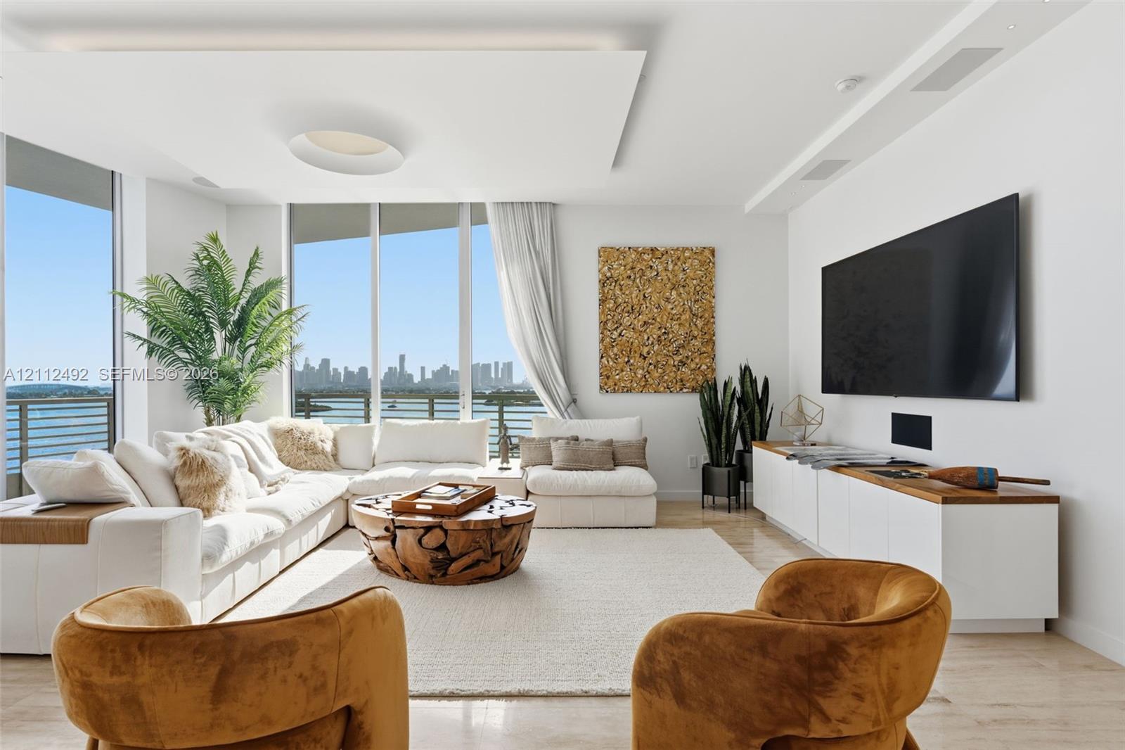 Living area featuring floor-to-ceiling windows, custom recessed tray ceiling with integrated lighting, polished stone flooring, and built-in low-profile cabinetry