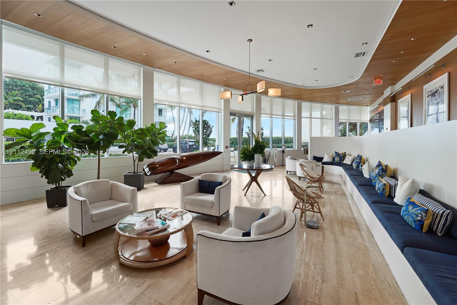 Floor-to-ceiling windows with integrated roller shades, stone flooring, curved wood-paneled ceiling, custom built-in bench seating, and multi-arm chandelier lighting