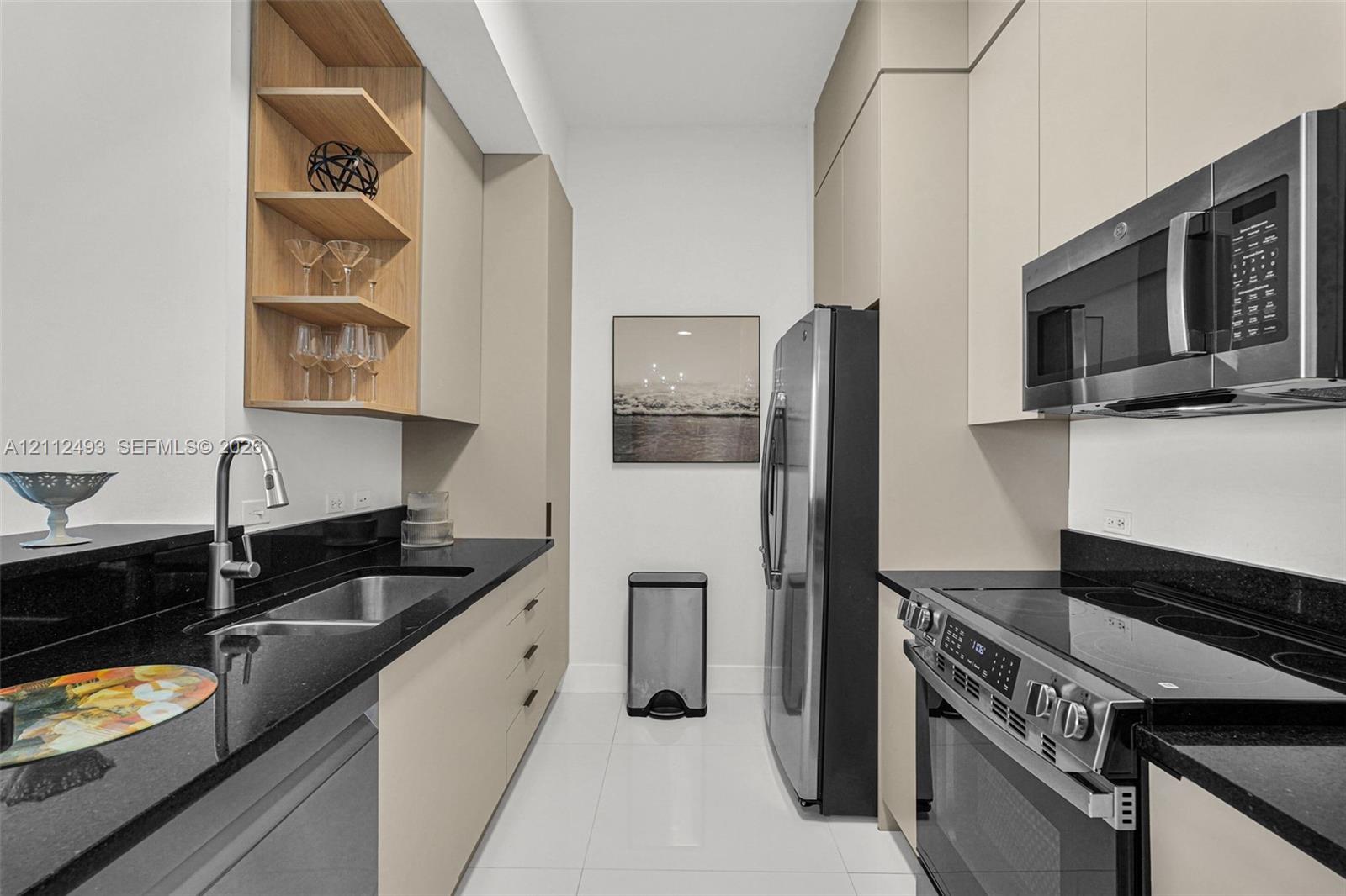 Kitchen featuring flat-panel cabinetry, open wood shelving, dark stone countertops, stainless steel appliances, and tile flooring