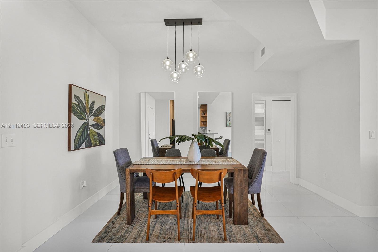 Dining space featuring high-gloss tile flooring, smooth ceiling finishes, and a contemporary multi-light glass pendant fixture