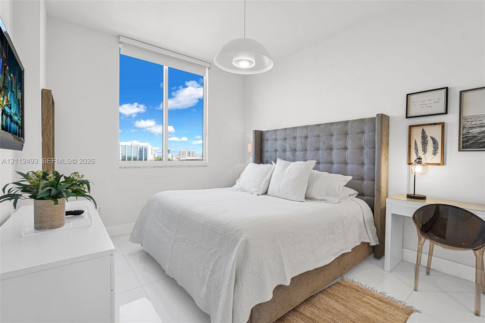 Large picture window with exterior scenery, neutral walls, white floor tiling, and a central pendant light fixture