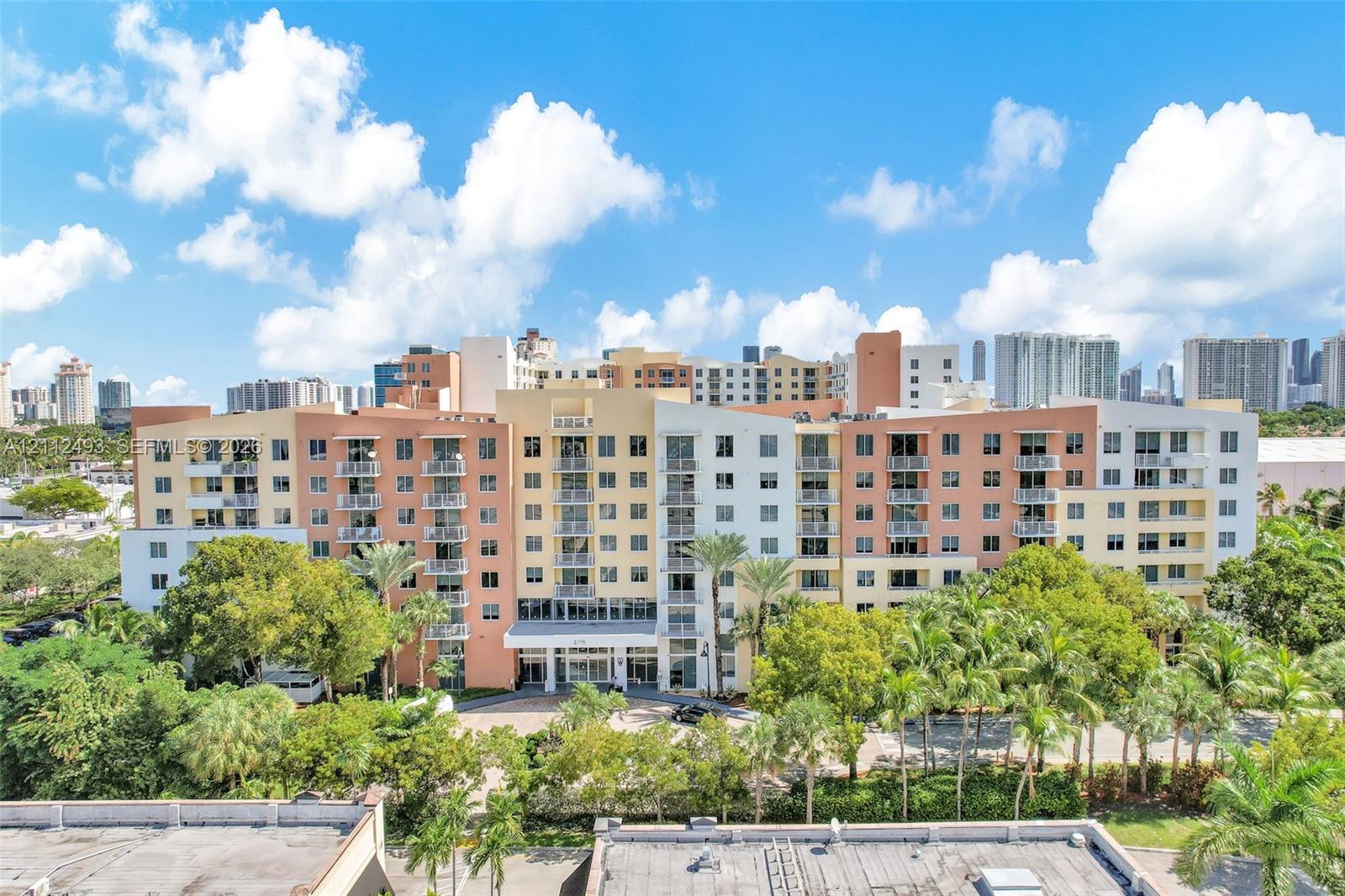 Multi-story residential complex featuring private balconies, expansive glass fenestration, and mature perimeter landscaping Multi-story residential complex featuring private balconies, expansive glass fenestration, and mature perimeter landscaping