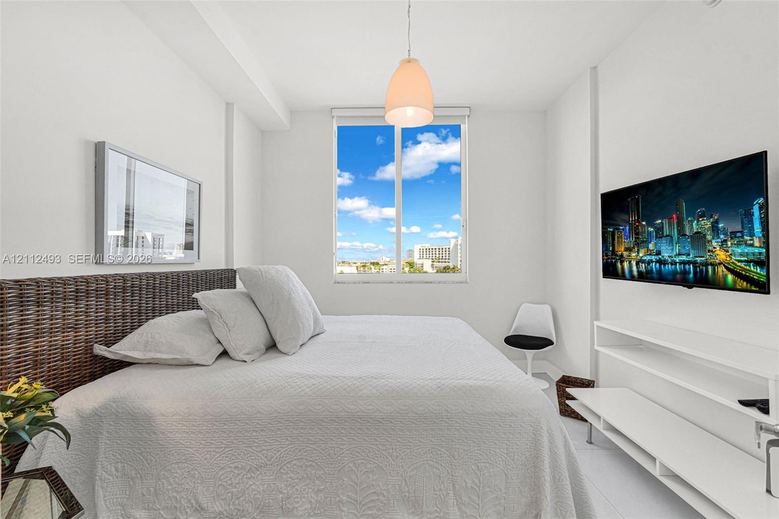 Bright interior featuring a single-light pendant fixture, white wall-mounted tiered shelving, and a large single-pane window with expansive exterior scenery