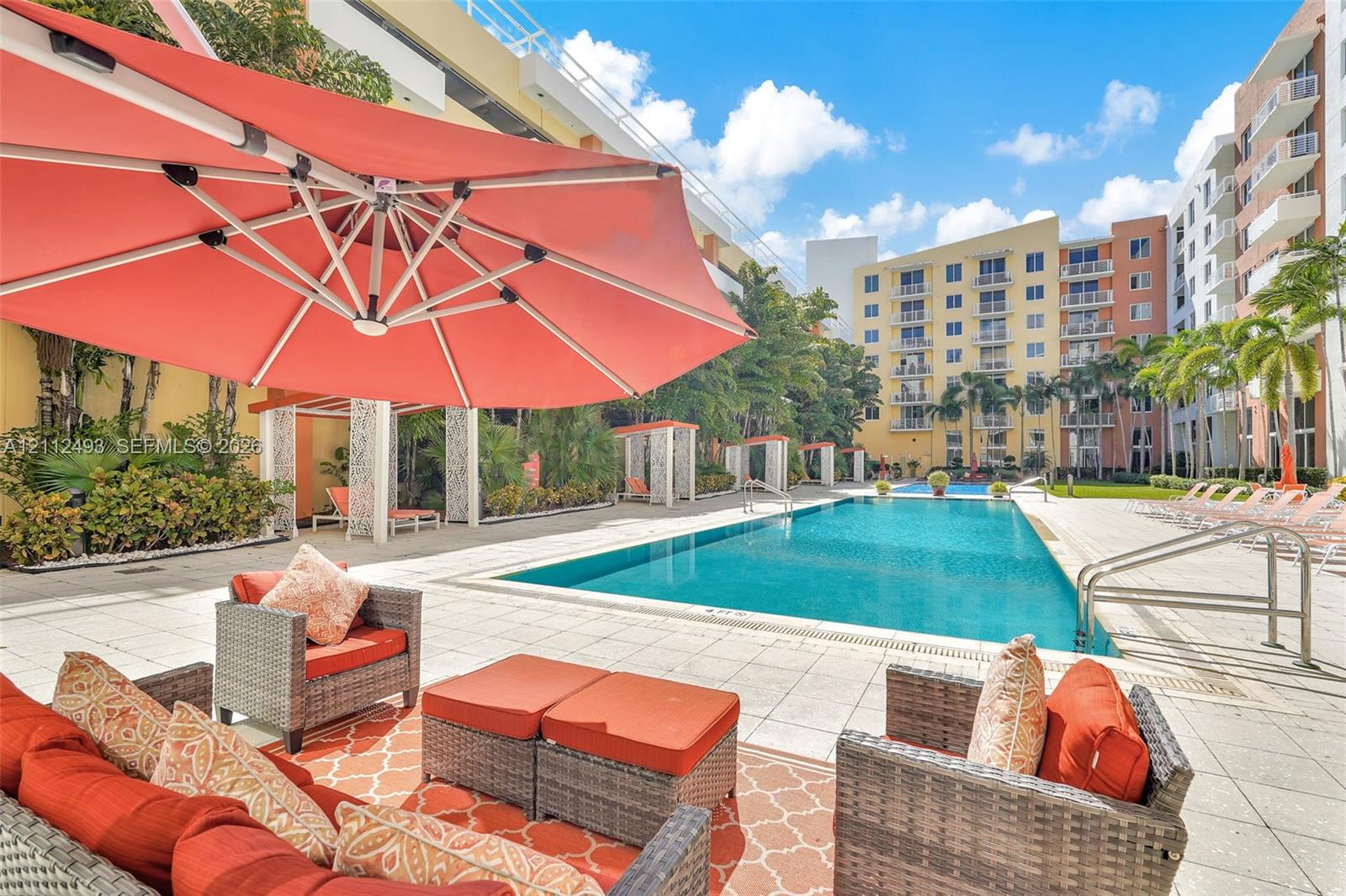 Swimming pool with tile surround, pergola-covered seating areas, and landscaping