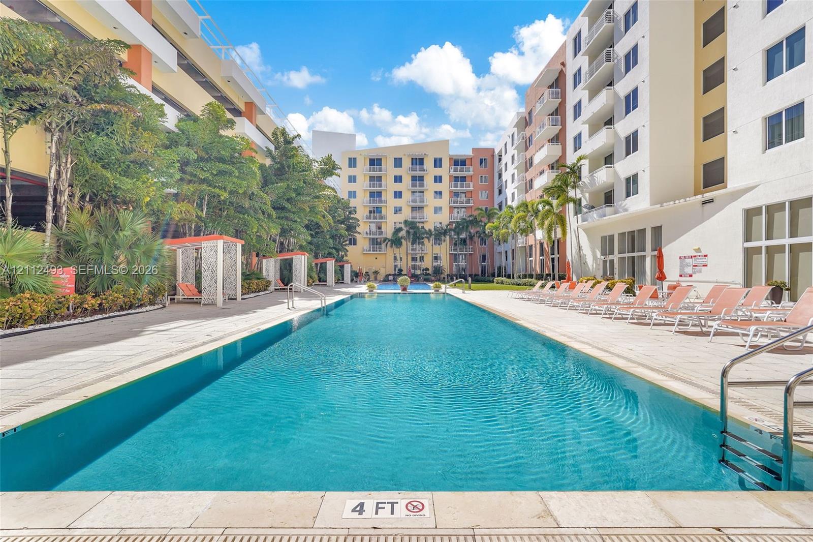 Lap pool featuring a stone-paver deck, built-in covered cabanas, and mature palm landscaping Lap pool featuring a stone-paver deck, built-in covered cabanas, and mature palm landscaping