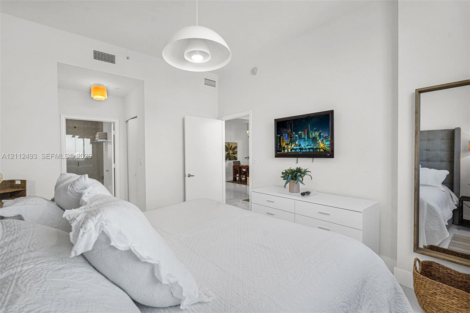 Spacious room featuring high ceilings, white walls, and a large white dome pendant light