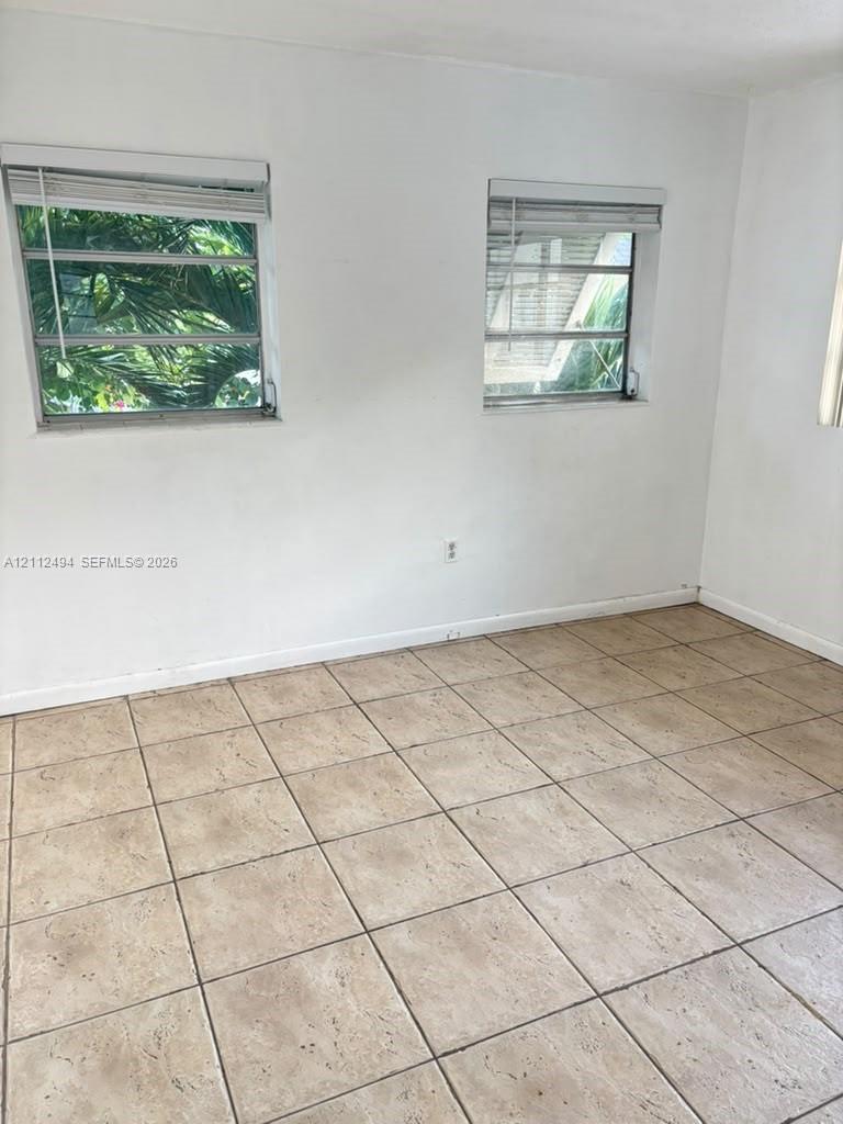 Neutral wall finishes, large-format square tile flooring, and two louvered-style windows