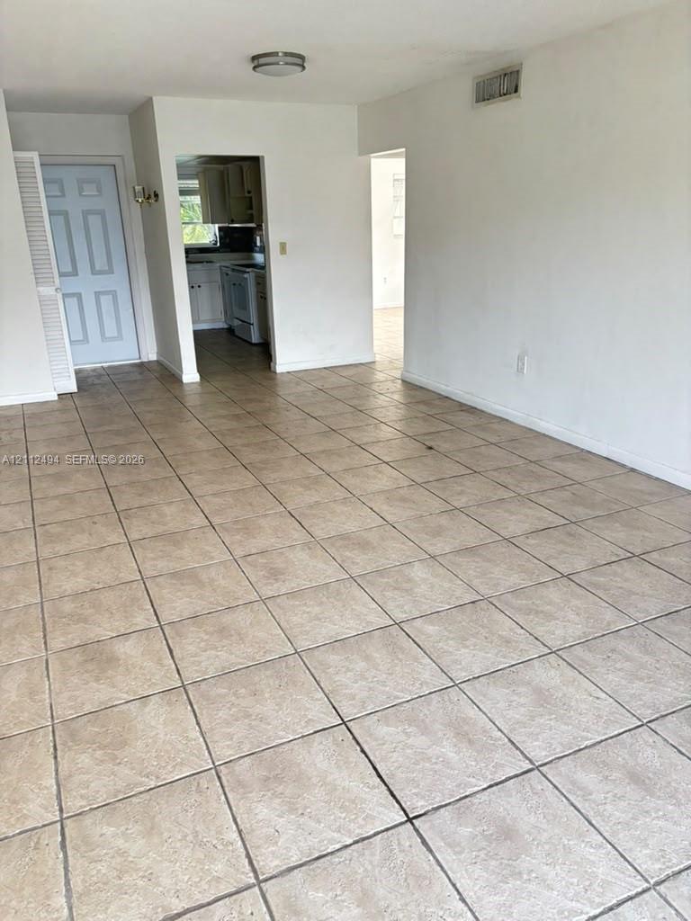 Ceramic tile flooring, neutral wall finishes, and solid-core interior door with louvered closet panel
