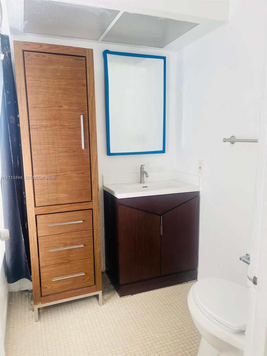 Bathroom featuring a dark wood-finish vanity with an integrated basin, a tall matching wood-finish storage cabinet, and a wall-mounted mirror