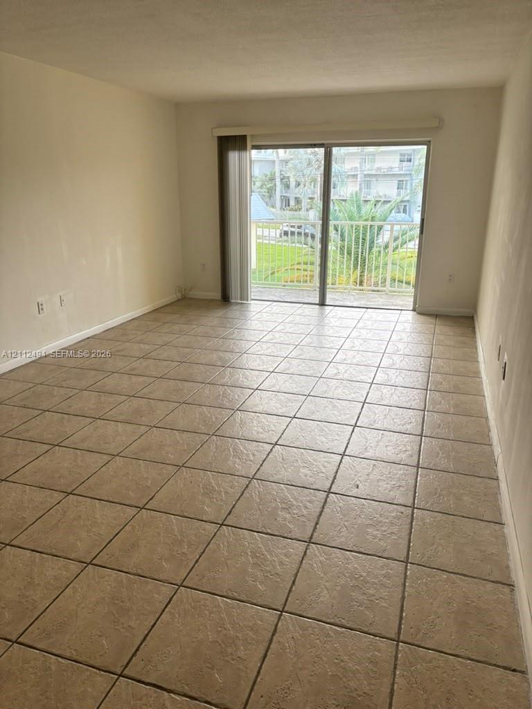 Neutral-toned ceramic tile flooring, sliding glass doors, and a metal-railing balcony