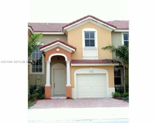 Stucco exterior featuring a tiled roof, covered entryway with decorative columns, a single-car garage, and paved driveway