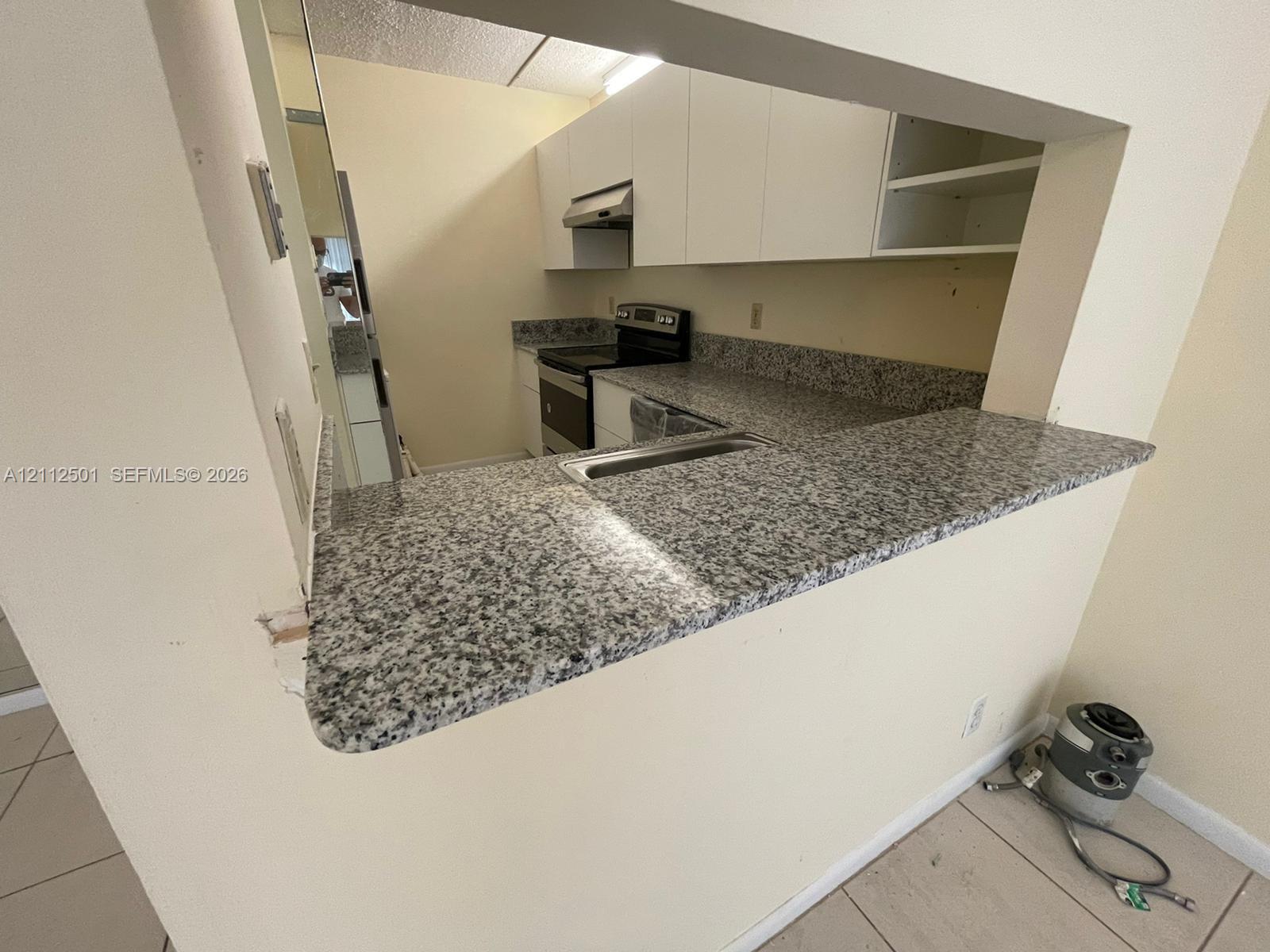Kitchen featuring stone-finish countertops, flat-panel cabinetry, stainless steel range, and an integrated pass-through breakfast bar