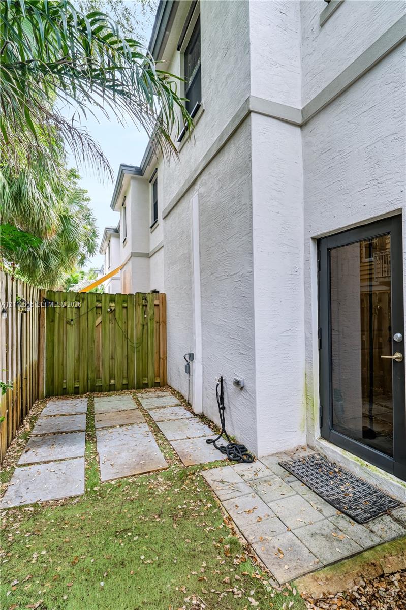 Exterior side yard featuring stucco siding, stone paver pathway, and enclosed wood fencing