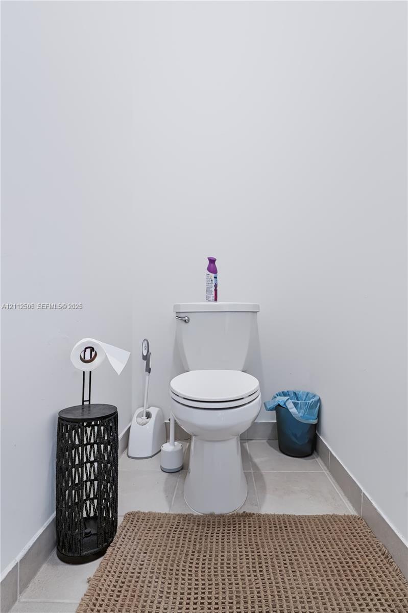 Standard-height white toilet with ceramic floor tiling