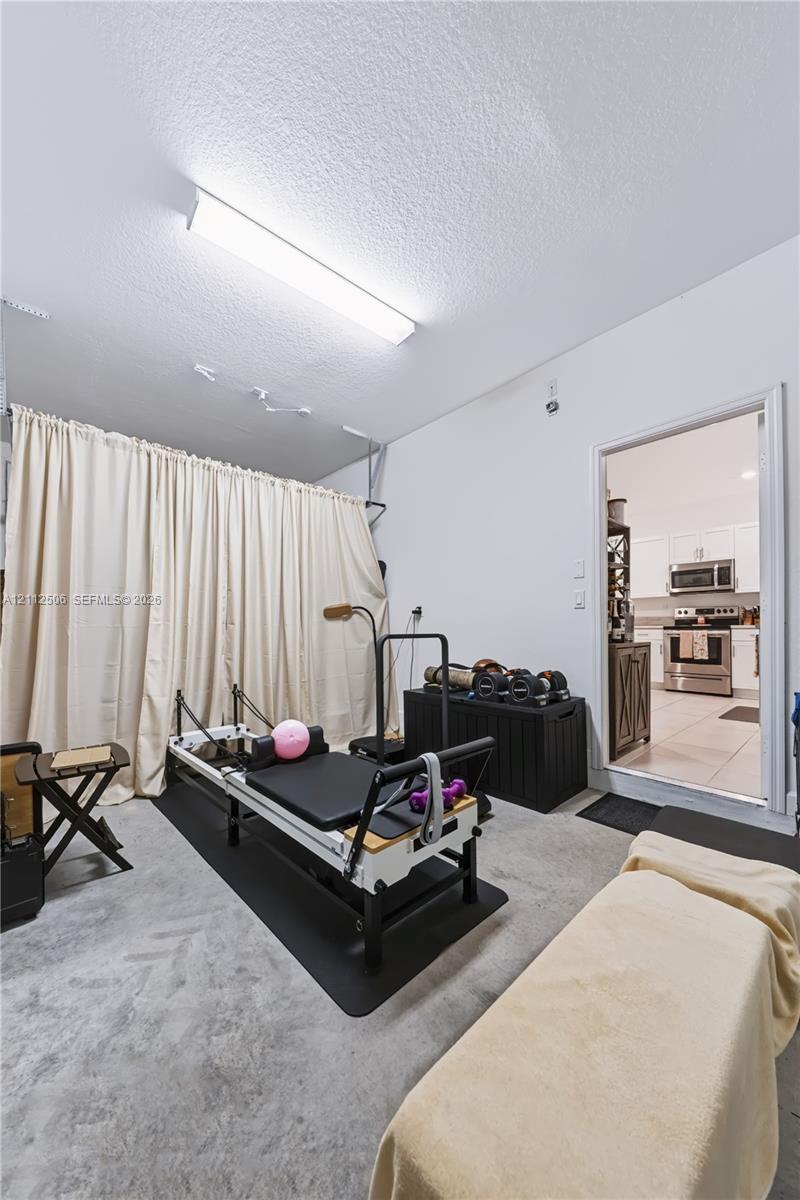 Flex space featuring concrete flooring, wall-mounted linear lighting, and a floor-to-ceiling curtain track system