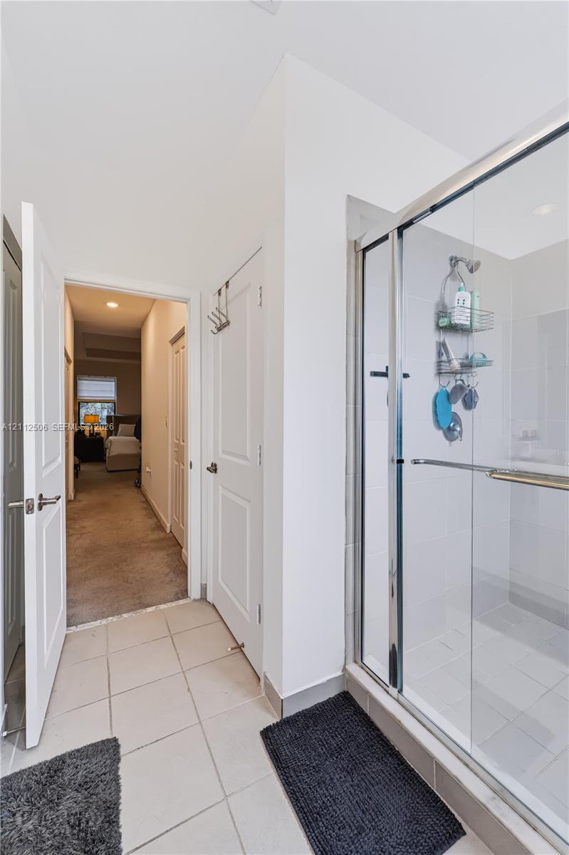 Walk-in shower featuring a glass enclosure, metal frame, and tile flooring
