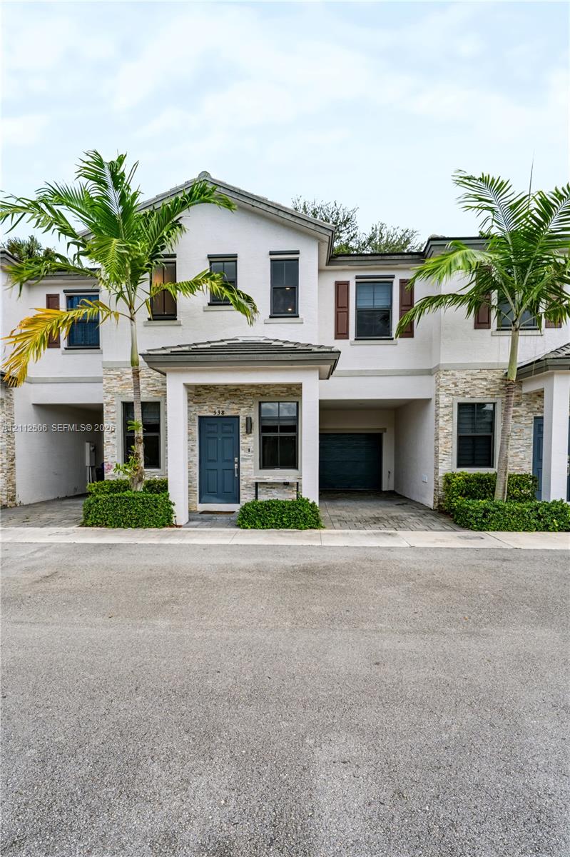 Two-story exterior featuring a stone veneer facade, integrated garage, covered entryway, and framed window shutters