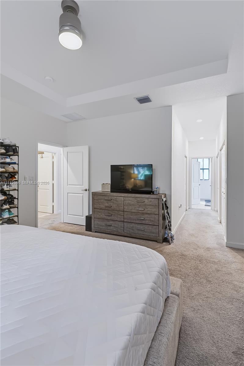 Interior room featuring a tray ceiling, wall-to-wall carpeting, and a modern cylinder-style ceiling light fixture