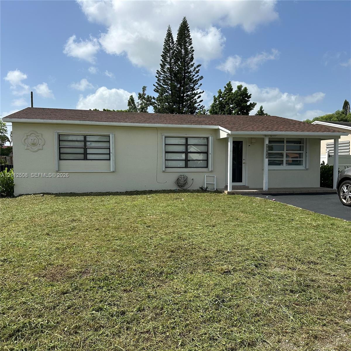 Single-story residence featuring a light-toned stucco exterior, shingled roof, covered front porch, and asphalt driveway Single-story residence featuring a light-toned stucco exterior, shingled roof, covered front porch, and asphalt driveway