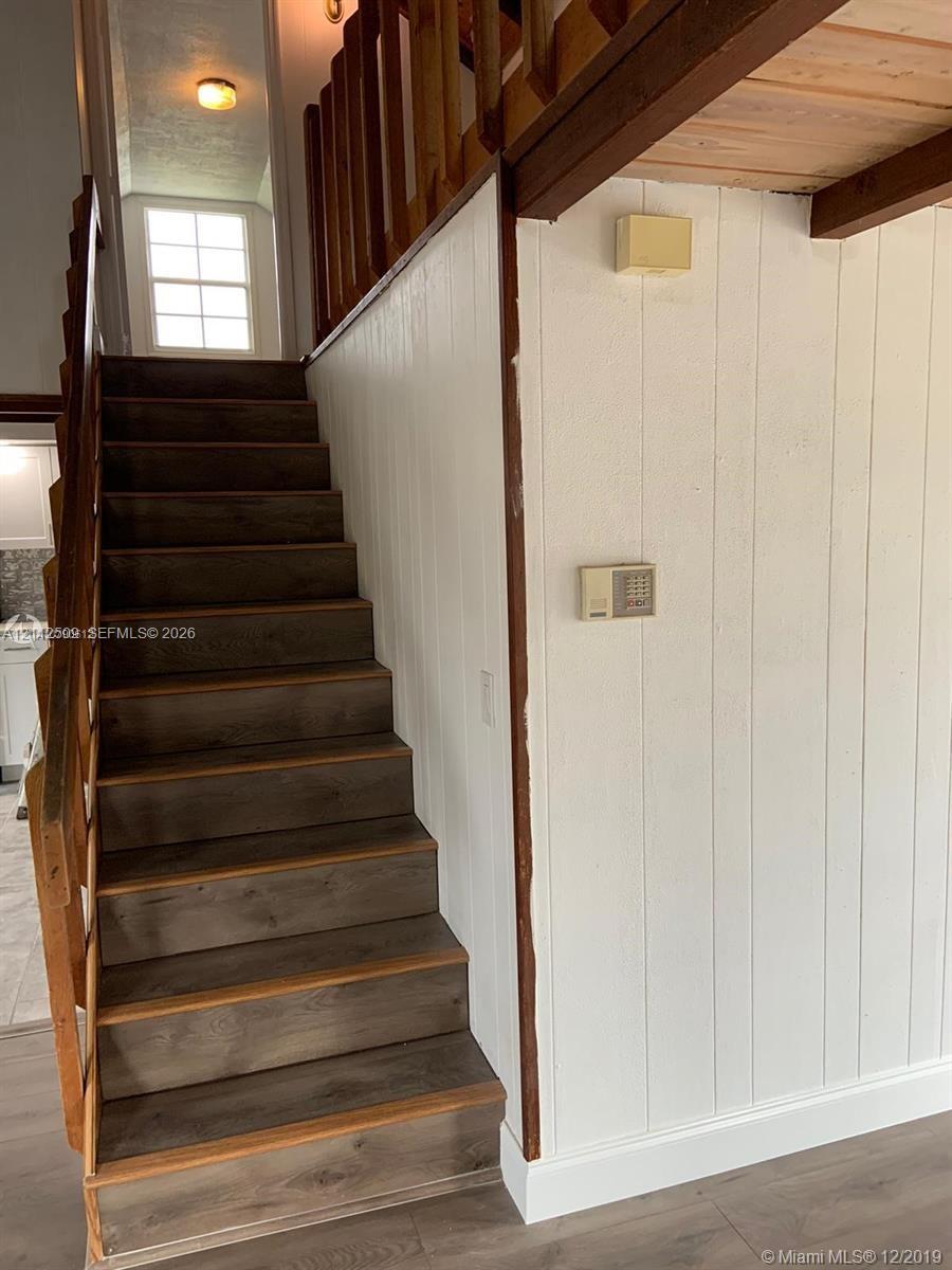 Staircase with wood-finish treads, vertical paneling, and a natural wood-finish railing