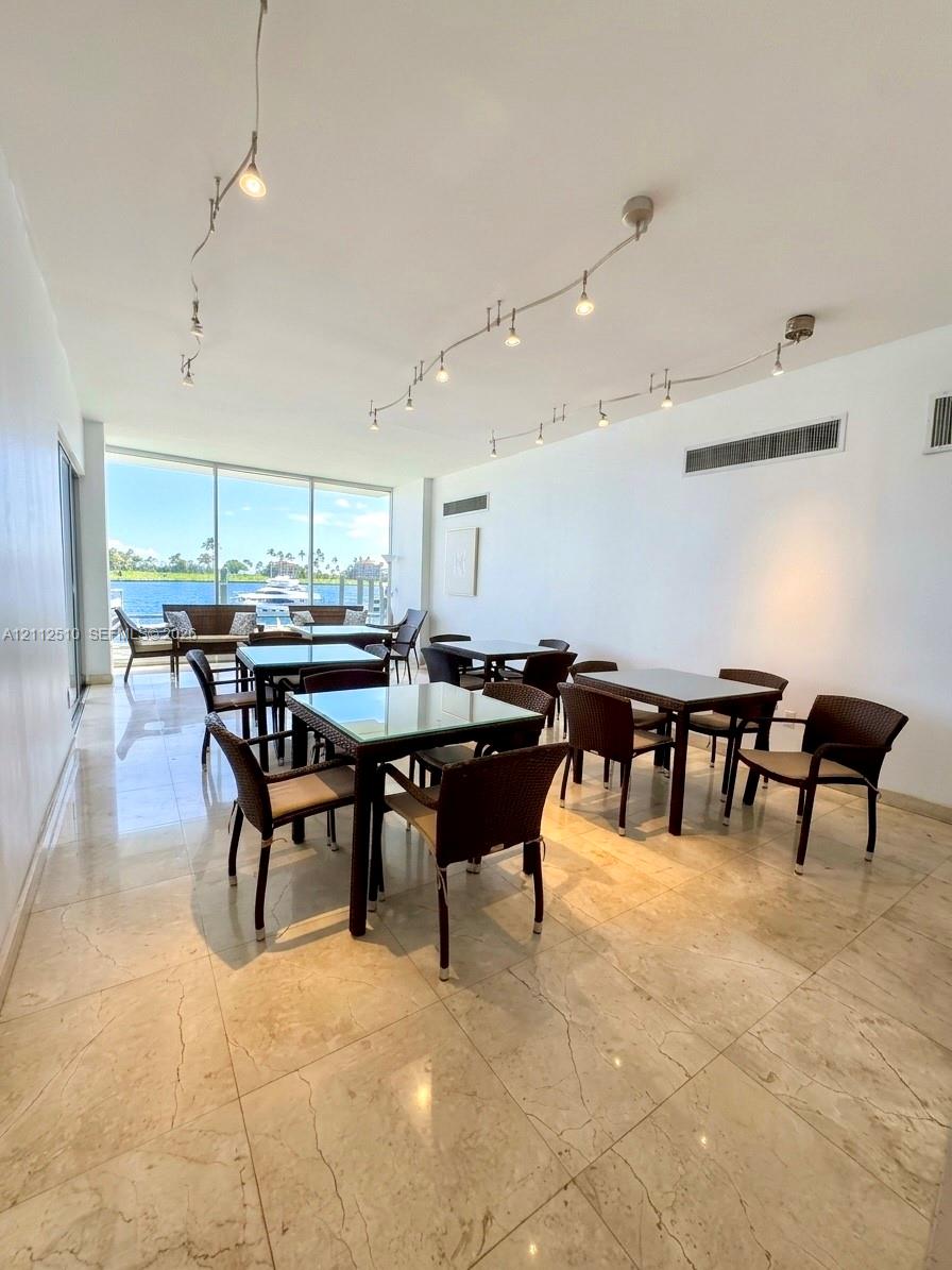 Open-concept interior featuring polished stone flooring, floor-to-ceiling windows, and multi-track ceiling lighting