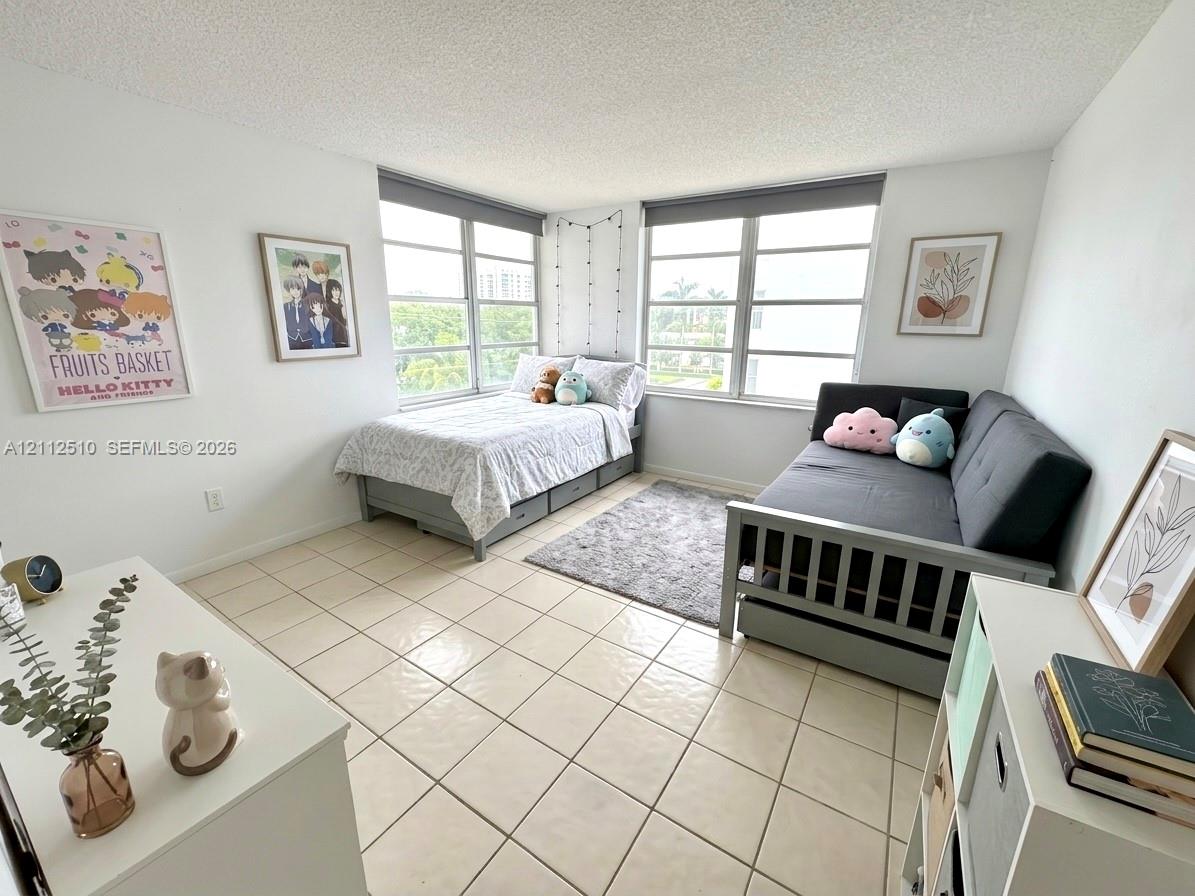 Bedroom featuring large windows, neutral ceramic tile flooring, and a textured ceiling