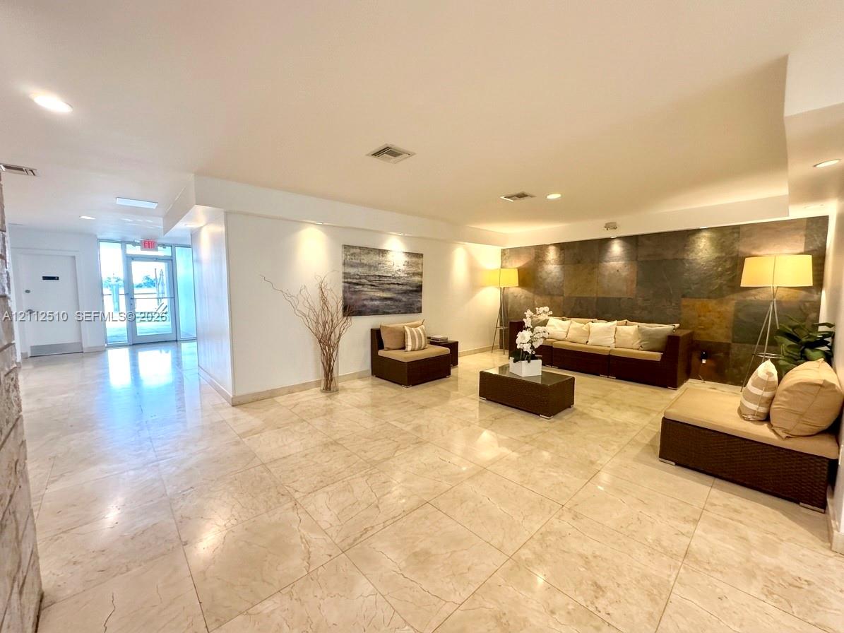 Large-format tile flooring, textured stone accent wall, and recessed ceiling lighting