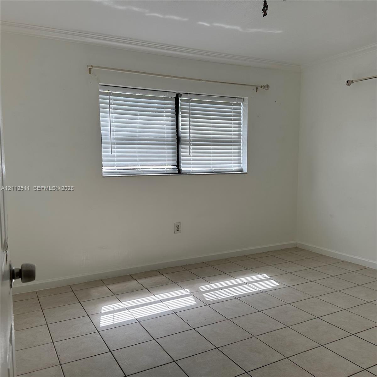 Interior room featuring ceramic tile flooring, neutral wall paint, and a window with horizontal blinds