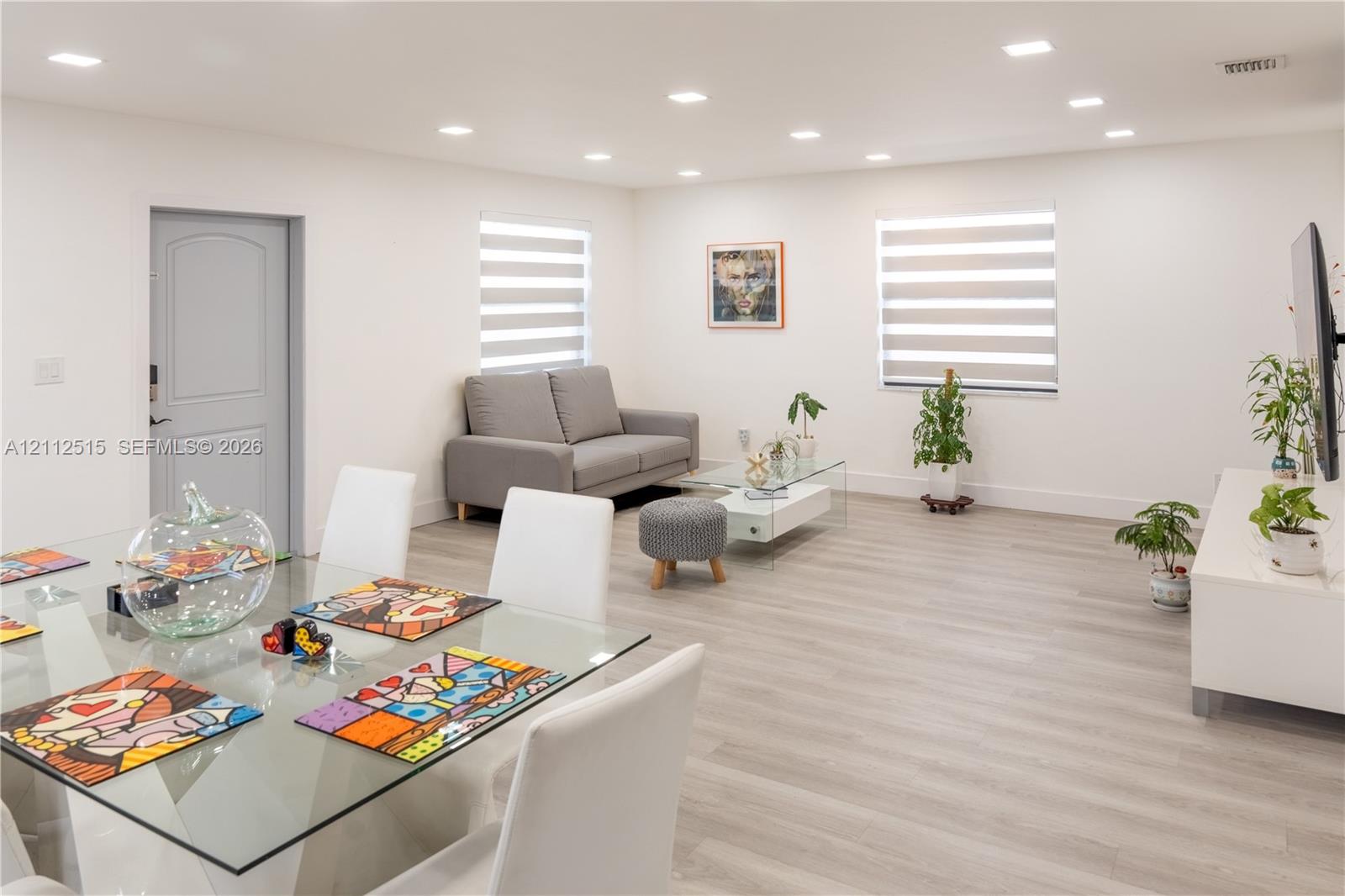 Open-concept living space featuring wood-finish flooring, recessed lighting, and banded window shades